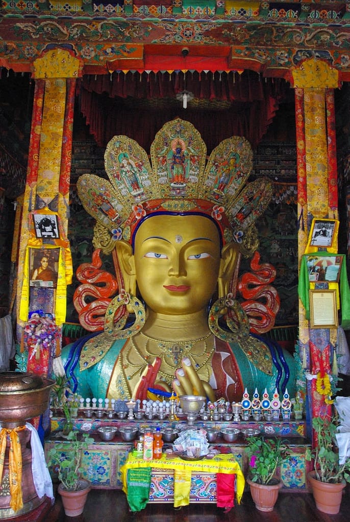 Divinité majestueuse aux traits apaisants, entourée d’offrandes et de symboles, au cœur d’un sanctuaire richement orné où chaque détail invite à la contemplation