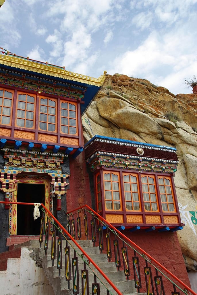 Temple aux façades richement colorées niché dans la roche, où l’architecture se fond avec la montagne sous un ciel paisible