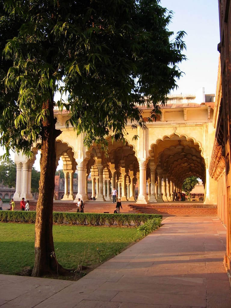 Galerie majestueuse aux arches infinies baignée de lumière dorée, où le temps semble ralentir à l’ombre des pierres sculptées