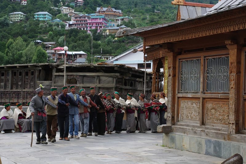 Danse collective traditionnelle devant un temple en bois, au cœur d’un village de montagne coloré (?)